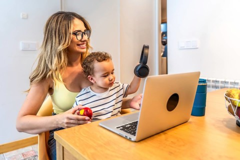 Mother and son sharing a moment of connection while using a laptop and headphones in their modern