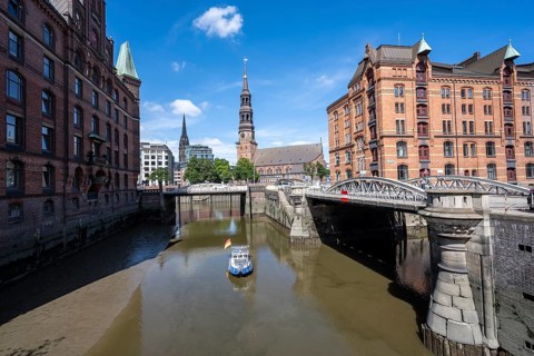 Boat on the Kleines Fleet canal with Kannengießer bridge and tower of the main church of St.