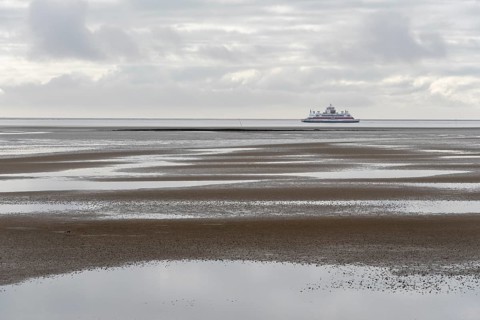 A ferry of the Wyker Dampfschiffs-Reederei (W.D.R.) sails at low tide in the Wadden Sea between