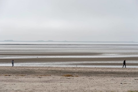 Two people walking on the wide beach of the island of Föhr, Schleswig-Holstein, Germany, at low