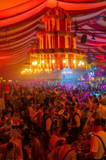 Large crowd celebrates in the festive light of a beautifully decorated marquee, Cannstatter Wasen