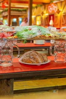 Close-up of beer mugs and packaged food on red tables in the marquee, Cannstatter Wasen folk