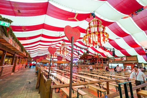 Cosy beer tent with red blankets, wooden benches and hearts as decoration, Volksfest Cannstatter