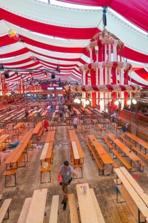 View of a festively decorated beer tent with red blankets and empty wooden benches, Volksfest