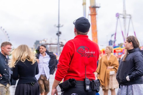 Security guard observing the action on a rainy Oktoberfest site, Cannstatter Wasen public festival,