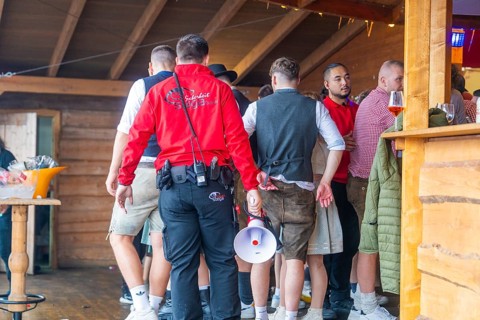 Group of people in traditional traditional costume crowding into an interior with wooden panelling,