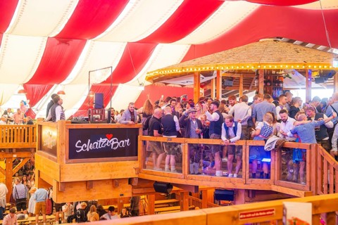 A crowded upper bar with people in traditional dress in a festively decorated room, Volksfest