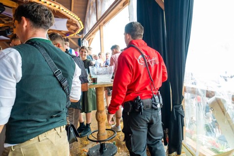 People in traditional traditional costume and security service stand in a crowded interior with