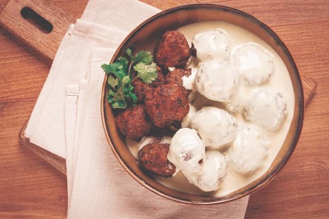 Swedish meatballs in cream sauce, plate on a wooden table, homemade, no people