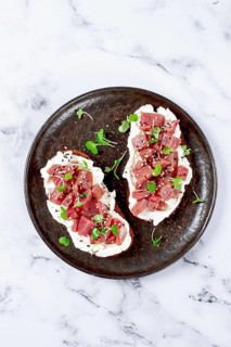 Sandwiches, rye bread with cream cheese, sliced tuna fillet with herbs, breakfast on a black plate,