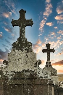 Two weathered crosses stand tall against a colorful sunset sky, showcasing the beauty of an ancient