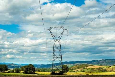 High voltage power lines against a bright blue sky with scattered clouds, Puy de Dome, Auvergne