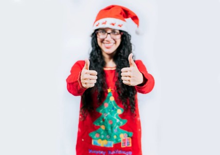 Young woman in Christmas sweater gesturing Ok with thumbs up. isolated. Smiling girl in Christmas