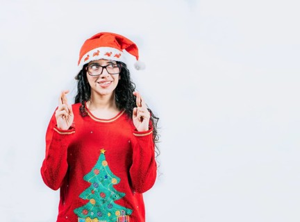 Young woman in Christmas sweater making a wish and crossing fingers. Beautiful girl in Christmas