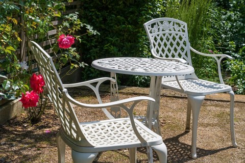 Sitting area in the garden, table and two garden chairs, framed by blooming roses, Westphalia,