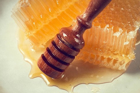 Honeycomb, with a wooden spoon-spindle, on a plate, no people