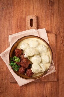 Swedish meatballs in cream sauce, plate on a wooden table, homemade, no people