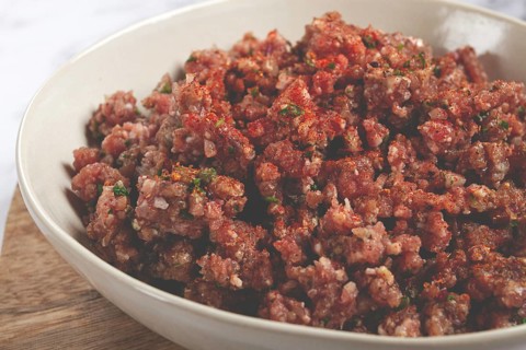 Raw minced meat, marinated with spices and herbs, in a bowl, minced meat with spices, top view,