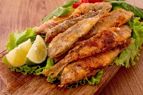Fried crispy red mullet fish, on a wooden chopping board, with lime, no people