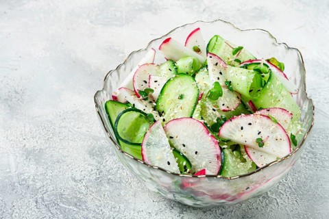 Crisp cucumber and thinly sliced radishes are mixed with fresh herbs in a decorative bowl. The dish