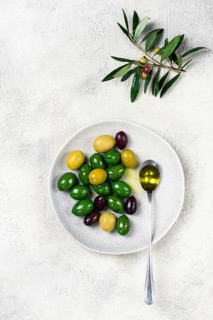 A mix of olives, a variety of Chalkidiki, verdi giganti and Kalamata, on a plate with a spoonful of