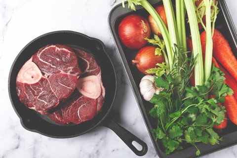 Sknuckle on the bone, raw meat for ossobuco, in a cast-iron pan, baking sheet with vegetables, top