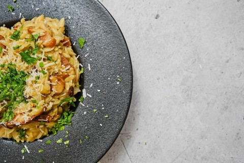 A delicious plate of risoni pasta combined with porcini mushrooms is presented beautifully. The