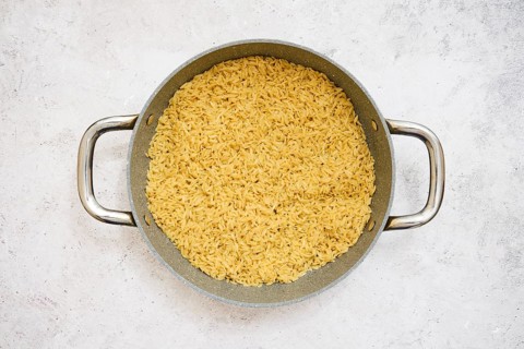 A pot filled with perfectly cooked risoni pasta on a neutral surface. This dish showcases a rich