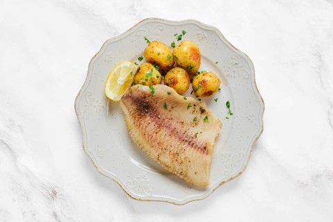 A perfectly grilled red seabream fish fillet alongside tender baby potatoes sprinkled with herbs. A