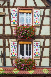 Decorated half-timbered house with ornate windows and flowers in the old town centre of Kaysersberg