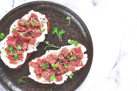 Sandwiches, rye bread with cream cheese, sliced tuna fillet with herbs, breakfast on a black plate,