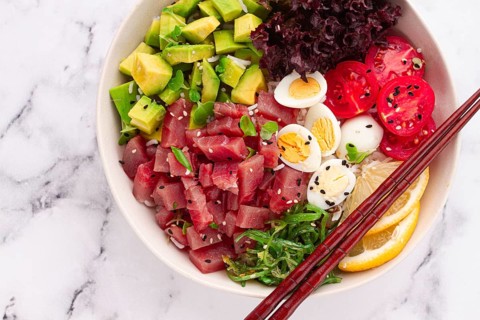 Fresh poke bowl, with tuna, avocado, and vegetables, served on a white plate