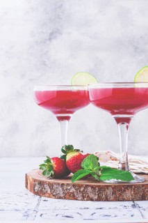 Refreshing cocktail in an elegant glass with lime and strawberries, sunshine, no people