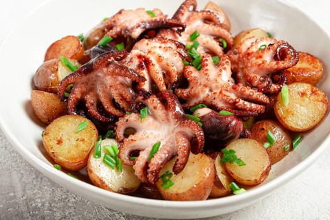 Baby grilled octopus with golden baked potatoes and fresh herbs, Maltese cuisine, homemade, no