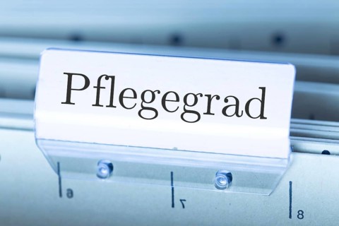 (Photomontage) Sign with the inscription PFLEGEGRAD on a suspension file folder