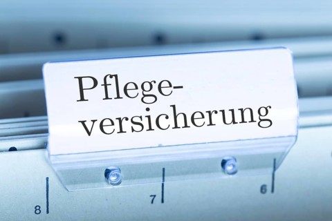 (Photomontage) Sign with the inscription PFLEGEVERSICHERUNG on a suspension file index