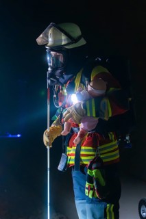Firefighter with breathing mask and child dummy during a night-time operation, firefighting