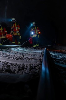 Rescue workers in the tunnel on railway tracks in the dark with blue lights, fire brigade exercise