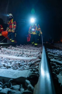 Firefighters on rails, the surroundings illuminated by emergency lighting, firefighting exercise in