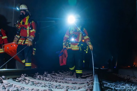 Two firefighters on tracks with headlamps at night, fire drill in the new construction tunnel of