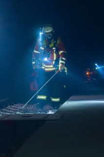 Firefighter examining railway track with lantern in a dark environment, firefighting exercise in