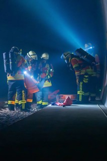 Firefighters working on the tracks at night, illuminated by helmet lamps, firefighting exercise in
