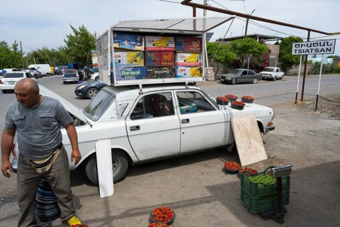 A car as an improvised roadside fruit market stall, selling fruit such as strawberries by the