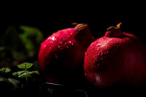 Two pomegranates with drops of water in a dark atmosphere