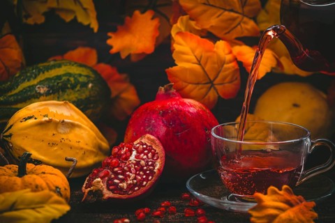 Tea is poured into a glass cup, pomegranate and pumpkins, autumnal atmosphere