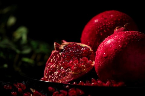Sliced pomegranate with protruding seeds in a dark atmosphere
