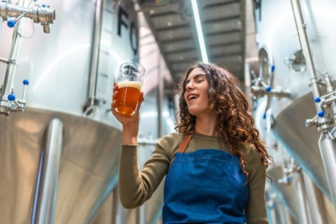Woman tasting craft beer for quality control, evaluating the quality of the beverage in a modern