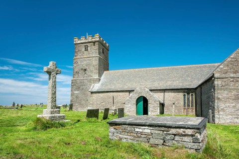 The Norman church of St Materiana with graveyard and stone cross, Tintagel, Cornwall, England,