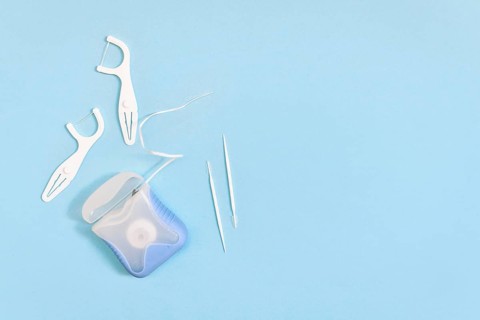 Dental floss and toothpicks on blue background with copy space. Oral hygiene products