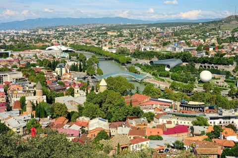Cityscape of Tbilisi with lush greenery and diverse architecture during a sunny days under a clear